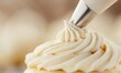 © NovaVision - A perfect swirl of vanilla frosting is being piped onto a cupcake with a pastry bag.
