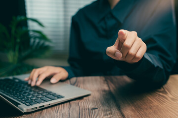 Poster - Close-up of Person Pointing at Camera with Laptop on Wooden Table in Workspace Environment, Business concept