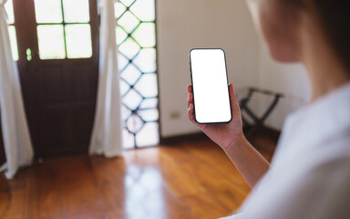 Wall Mural - mockup image of a woman holding mobile phone with blank desktop screen at home