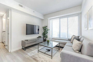 Poster - A photo of the interior design of an apartment living room, with white walls, a grey sofa, and a glass coffee table. 