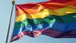 © Alex - A dynamic rainbow flag with six bold stripes representing diversity, equality, and LGBTQ+ pride, waving vibrantly under a bright blue sky to honor Pride Month and its inclusive message