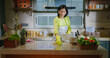 © Raushan_films - Indian gen x mature adult mom wear apron and hand gloves collect pick up waste trash in box use rag. Middle aged woman lady do work use rag wiping dust on table keep modern kitchen neat clean tidy