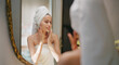 © Raushan_films - Indian young adult gen z woman lady teen girl female wrapped towel on head and body look mirror do self skin care face wash day home
