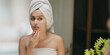 © Raushan_films - Indian upset young adult gen z woman lady wrapped towel on head and body look mirror feel sad facial pores skin dry cheek teen girl female worried for acne pimple touch face heath care at indoor home