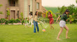 © Raushan_films - Indian happy teen girl lady mom hold hose pipe spray water on family group play game house lawn cute kid boy son child young adult man have fun joy day spend funny time enjoy trip outside picnic park