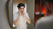 © Raushan_films - Indian Asian gen z young adult single happy man male guy smiling look mirror touch beard daily care routine feel proud good ready for new Joyful day enjoy indoor house