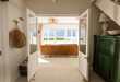 © Wavebreak Media - Cozy beach house living room with ocean view through open double doors, copy space