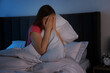 © New Africa - Fear of darkness. Scared young woman on bed and hiding her face in room at night