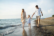 © ADDICTIVE STOCK - Happy family walking barefoot on a sandy beach at sunset