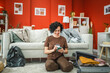 © Miljan Živković - woman sit on floor near suitcase and have online shopping on cellphone