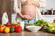 © Pixel-Shot - Healthy food on table against pregnant woman in kitchen, closeup