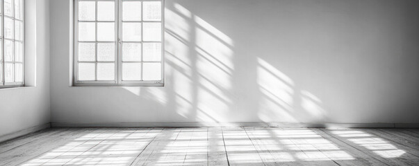 Poster - A large empty room with a window that lets in sunlight. The room is very bright and open, with a lot of natural light coming in. The walls are white, which makes the room feel even more spacious