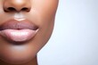 © Margarita Ratatosk - Close-up of african american woman's plump lips with glossy pink lipstick. Beauty treatment, cosmetic concept. Lip care and makeup application for enhancing natural beauty.
