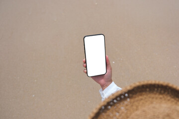 Wall Mural - top view mockup image of a woman holding mobile phone with blank desktop screen by the sea
