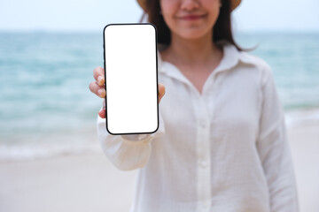 Wall Mural - mockup image of a woman holding and showing mobile phone with blank desktop screen by the sea
