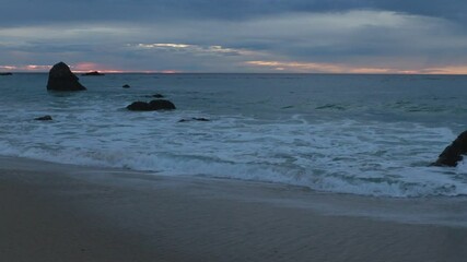 Wall Mural - golden sunset on a beach, foamy waves rolling towards white sand beach under low the sun light