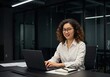 © Poetra RH - A young professional Chinese woman working on his laptop in a modern office. He is smiling, engaged, and productive. remote work, and business efficiency.