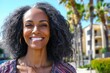 © Leo Rohmann - Mature woman with voluminous natural curly hair standing outdoors in bright daylight with radiant smile embodying positivity self confidence and expressive individuality