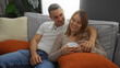 © Krakenimages.com - Man and woman relaxing in cozy living room, enjoying quality time together in a loving atmosphere, highlighting a strong relationship with hispanic warmth and comfort.