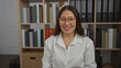 © Krakenimages.com - Young, attractive, brunette, hispanic, woman smiling in a workplace office with shelves filled with folders behind her