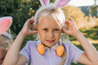 © ADDICTIVE STOCK - Girl with bunny ears and Easter egg earrings outdoors