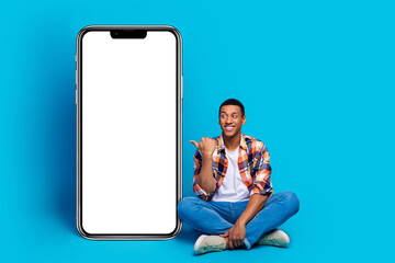 Full size photo of nice young man indicate finger empty space poster wear shirt isolated on blue color background