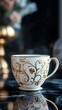 © Georg - Elegant tea cup with gold floral design on a marble surface in a dimly lit room