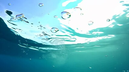 Poster - A clear blue ocean with many bubbles. The bubbles are scattered throughout the water. The water is calm and peaceful