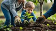 © Nathan - A young boy with blonde hair helps his mother plant a sapling in rich soil, fostering a love for nature and gardening.