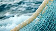 © chusnul - Close-up of a fishing net with a textured rope against a backdrop of ocean waves