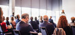 © kasto - Business and entrepreneurship symposium. Female speaker giving a talk at business meeting. Audience in conference hall. Rear view of unrecognized participant in audience.