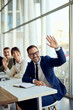 © bnenin - Group of Business Colleagues Smiling and Waving Inside a Bright Office Meeting Room