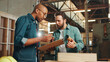 © peopleimages.com - Carpentry, talking and men in workshop with clipboard for woodwork, furniture restoration and lumber manufacturing. Construction, planning and people with planks, timber and board for renovation