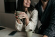 © La Famiglia - Smiling woman wearing bathrobe holding mug and enjoying morning coffee with partner