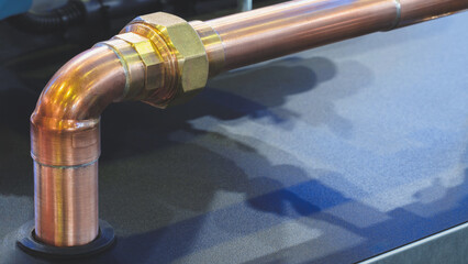 Aufkleber - A copper pipe is bent and has a gold colored cap. The pipe is on a black surface