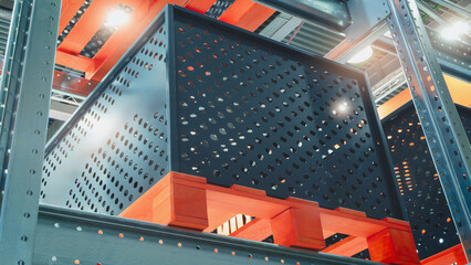 Fototapete - A warehouse with a lot of red and black boxes stacked on top of each other. The boxes are made of wood and are placed on a metal rack. The warehouse is well lit