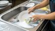 © stockpro - Person Engaged in Washing Dishes with Soapy Water and Sponge