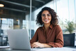 © Macrostock - Smiling portrait professional it specialist latin hispanic business lady working on laptop pc sitting in modern office. Young middle eastern indian woman using computer technology for work. Copy space