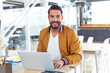 © WavebreakMediaMicro - Smiling man using laptop at office desk, working confidently on project