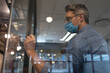 © Wavebreak Media - Businessman wearing mask writing on glass board in modern office environment