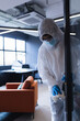 © Wavebreak Media - Person in protective suit cleaning office door handle, ensuring workplace safety, copy space