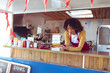 © Wavebreak Media - Food truck worker using smartphone, leaning on counter, smiling and relaxed