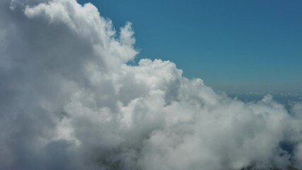 Wall Mural - flying through beautiful white fluffy clouds in blue sky. airplane travel background, 4k