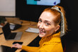 © Wavebreak Media - Smiling woman in yellow sweater working on laptop at office desk