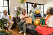 © Wavebreak Media - Diverse senior friends exchanging gifts and laughing in cozy living room celebration, at home