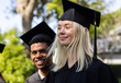 © Wavebreak Media - Graduating diverse students wearing caps and gowns smiling in garden, celebrating achievement