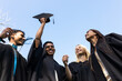© Wavebreak Media - Diverse graduates celebrating in garden, smiling and holding caps under clear blue sky