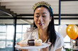 © Wavebreak Media - Smiling woman blowing candles on cupcakes during office birthday celebration