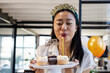 © Wavebreak Media - Asian woman celebrating birthday at office, blowing candle on cupcakes