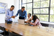 © Wavebreak Media - Diverse business team collaborating on laptop in bright office meeting room